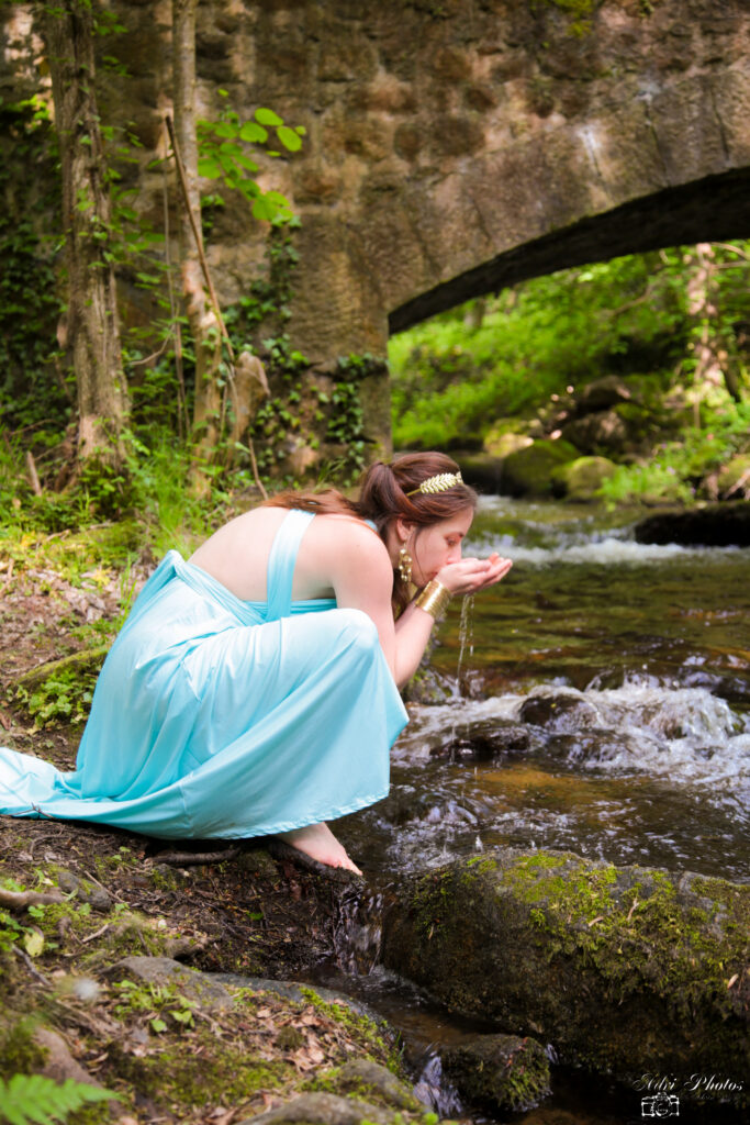 Photographe Montbrison jeune femme en robe bleue boit au bord de l'eau