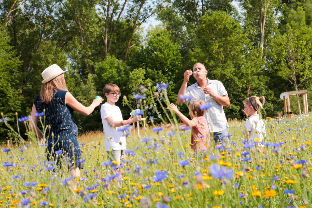 Famille jouant avec des bulles dans un pré fleuri