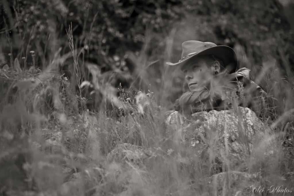 Photo noir et blanc, Indiana observe au loin derrière un champ de blé