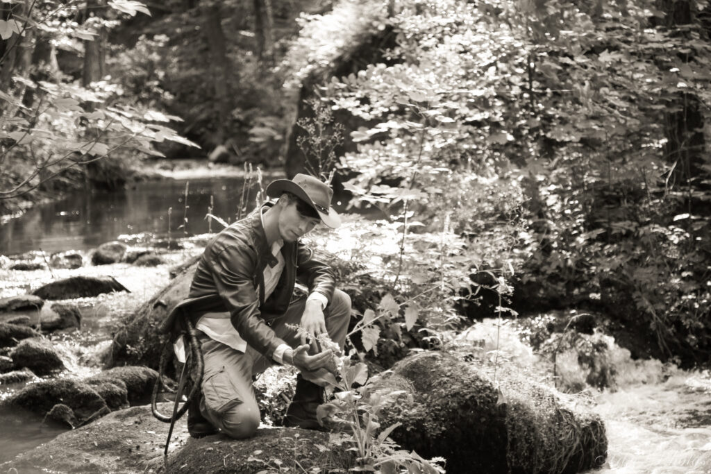 Indy observe une plante au milieu d'une rivière. Photos noir et blanc